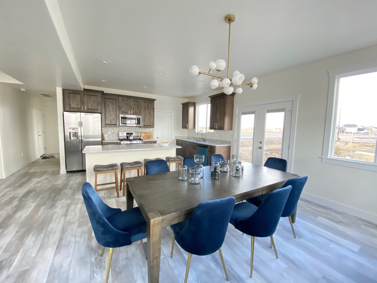 Dining area with blue chairs opening into a kitchen