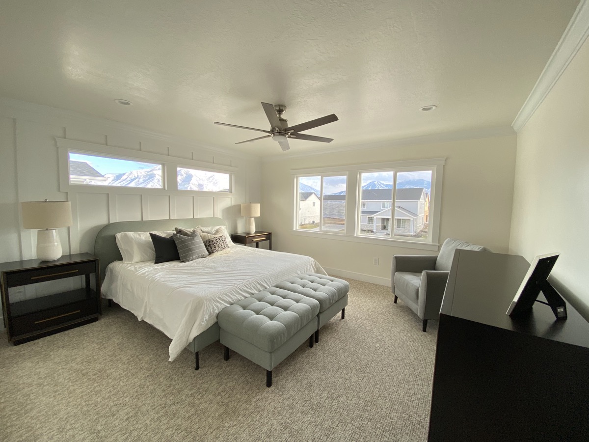 Primary bedroom with neutral furnishings and broad windows