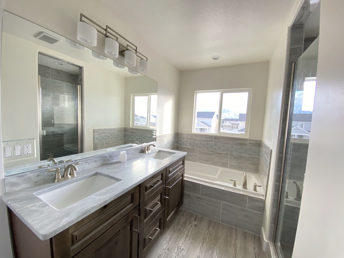 Primary bathroom with double vanity, tub, and glass shower