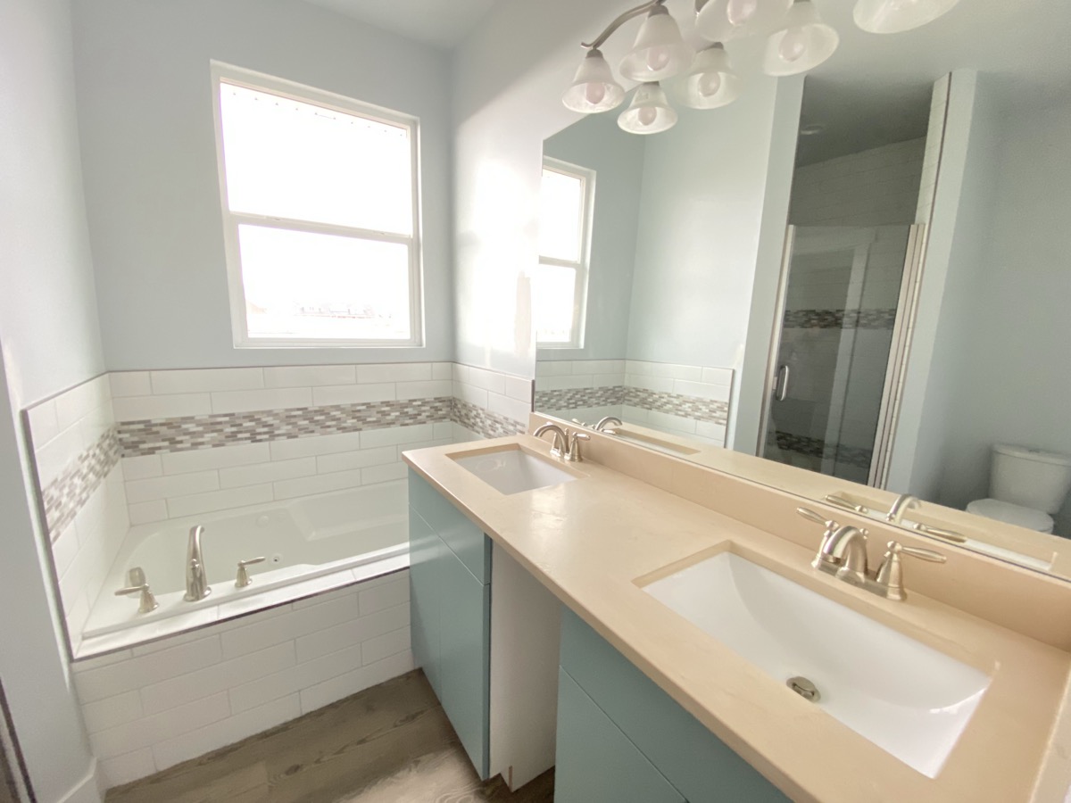 Bright bathroom with a blue double vanity and tub