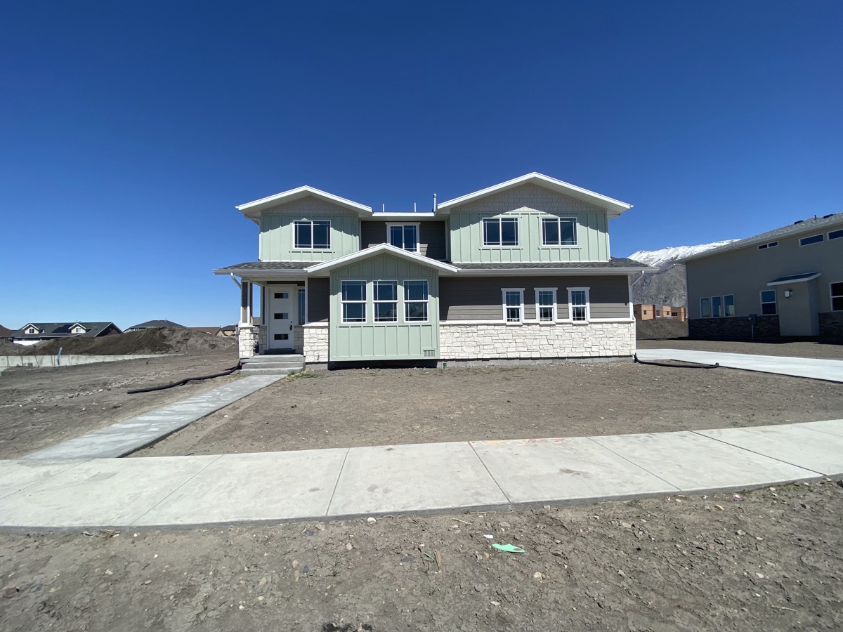 Two level green and gray home under a clear blue sky
