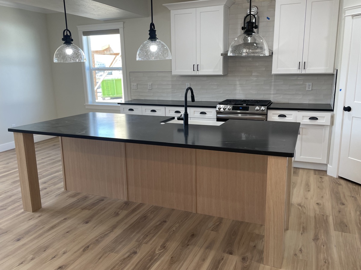 White kitchen with black counters and a natural wood island