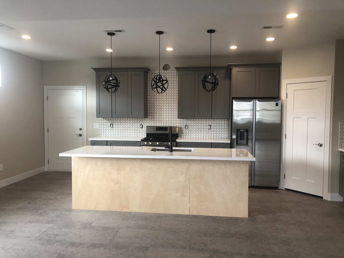Two tone kitchen with charcoal cabinets and a pale wood island